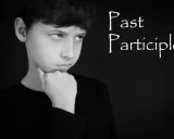 Chłopiec zamyślony, z podpartą brodą, jakby zastanawiał się nad trudnym zadaniem, być może nad gramatyką i formą **czas past participle**.