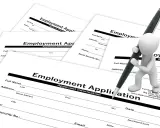 Biała figurka z długopisem wypełnia formularz "Employment Application" (ogłoszenie o pracę po ang.).