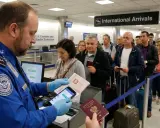 Kontrola paszportowa na lotnisku w USA. Urzędnik TSA sprawdza dokumenty podróżnych, wśród których widać osoby z polskimi paszportami.