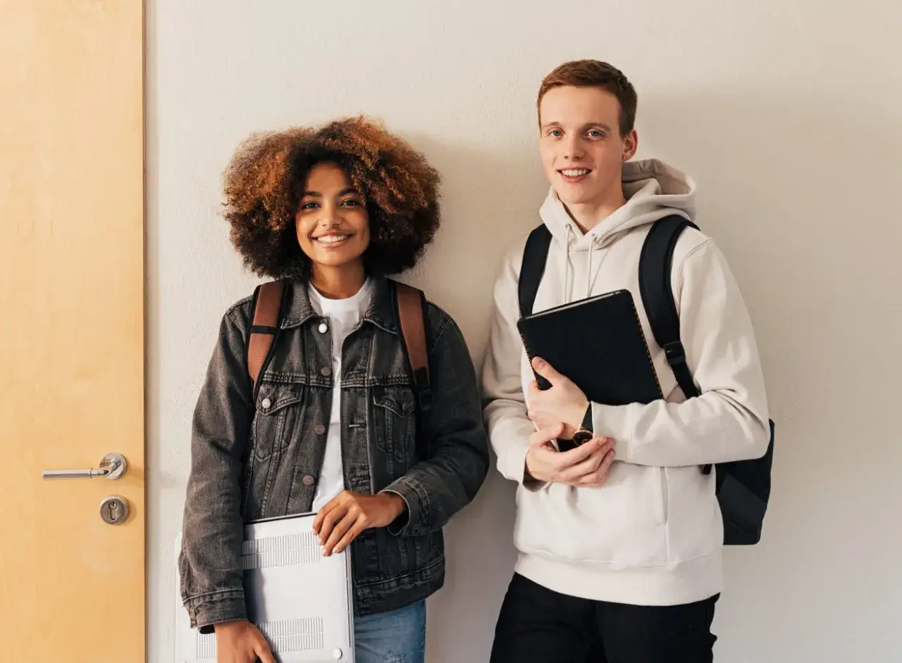 Dwóch studentów, dziewczyna z burzą loków i chłopak z rudymi włosami, przygotowuje się do nauki. Może właśnie szukają informacji, jak napisać artykuł po angielsku.